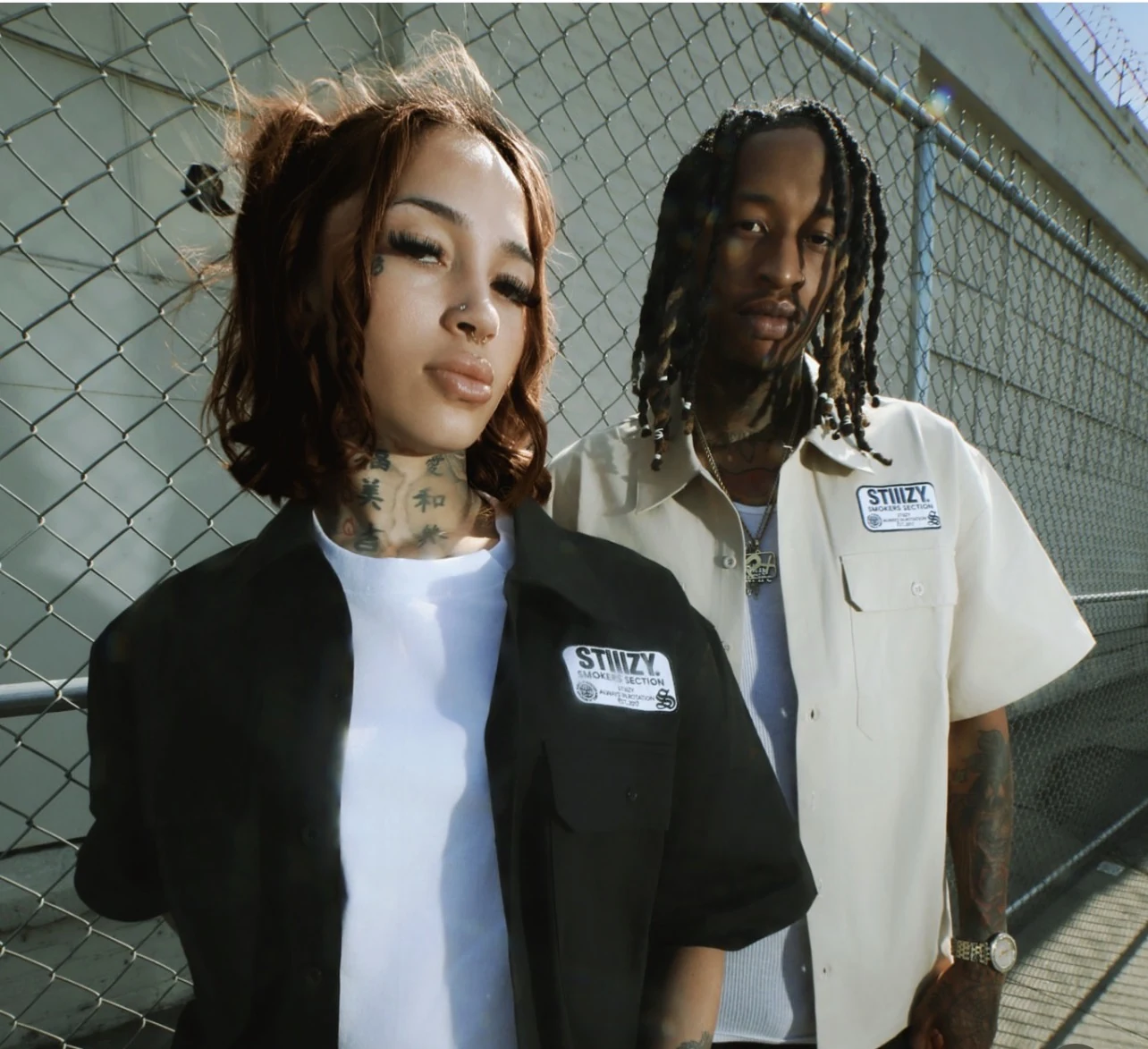 STIIIZY black and cream work shirts photographed beside a chain-link fence